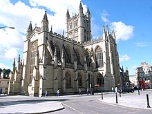 Yellow stone building with large arched windows and a tower.