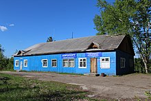 Photographie d'un bâtiment en bois bleu ne possédant pas d'étage, avec un toit en pente.