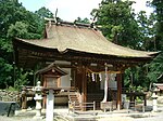 A small wooden building with a roofed, raised veranda with a handrail