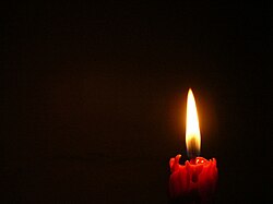 a single candle against a dark background, offset to the right