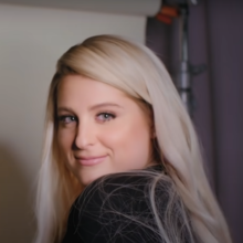 Meghan Trainor smiling and looking over her shoulder towards the camera