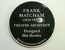 A dark green, circular plaque with the words "Frank Matcham (1854–1920) Theatre Architect Designed this theatre The Frank Matcham Society" in gold lettering.