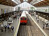 The interior of a building with windows on the ceiling and a railway track running from the background to the foreground in the centre