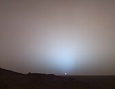 Solnedgång på planeten Mars, fotograferad av NASA:s rymdfordon Mars Rover från Mars den 19 maj 2005. Eftersom Mars inte har någon atmosfär har inte himlen här någon aftonrodnad utan det vita solljuset avtar bara alltmer när solen försvinner under horisonten. Att solen ser mycket mindre ut än från jorden beror på att Mars befinner sig cirka 100 miljoner km längre bort från solen.