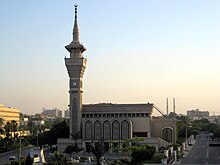 Photographie de l'avant d'une mosquée avec une horloge dans son unique minaret