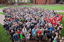 A large group of people seen from above. Everyone is looking at the camera.