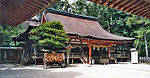 Wooden building with raised floor, vermillion red beams and railed open veranda.