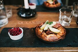 Swedish äggakaka with slices of pork belly, apples, and a bowl of lingonberries