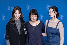 Trois femmes de face, posant devant un fond bleu.