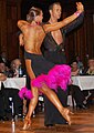 Image 20Latin dancers in their costumes. The woman is wearing backless dress with deep slits on its lower portion, while the man is wearing a shirt with top buttons open. (from Fashion)