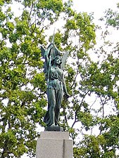 A woman raising a flag and holding a broken chain