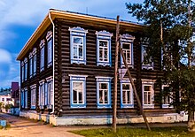 Photographie d'un bâtiment en bois marron avec les cadres des fenêtres bleues possédant deux étages.