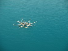 Outrigger boat surrounded by nets raised on bamboo poles