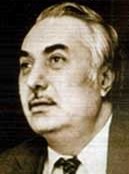 Three-quarter profile publicity shot of clean-shaven man with slight moustache, heavy eyebrows and short hair brushed back