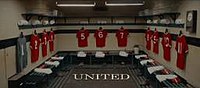 A changing room with red shirts hanging on pegs.