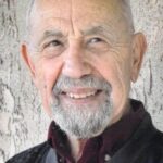 Headshot of Lew Palter smiling against stucco wall