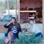 Two women sitting outside drinking wine.