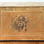 Picture of a gold box with a sculpted relief of a family on the front.