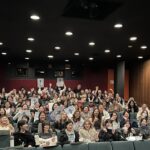 Students sitting in the Bijou theater, with several holding up Moana 2 posters