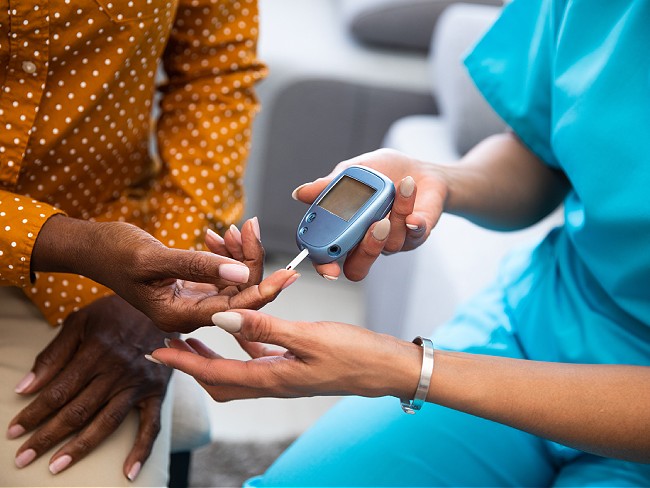 Nurse helping patient with blood glucose monitor