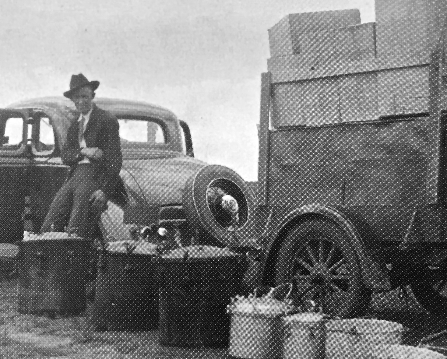 Man and a row of pressure cooker aligned next to a car and trail