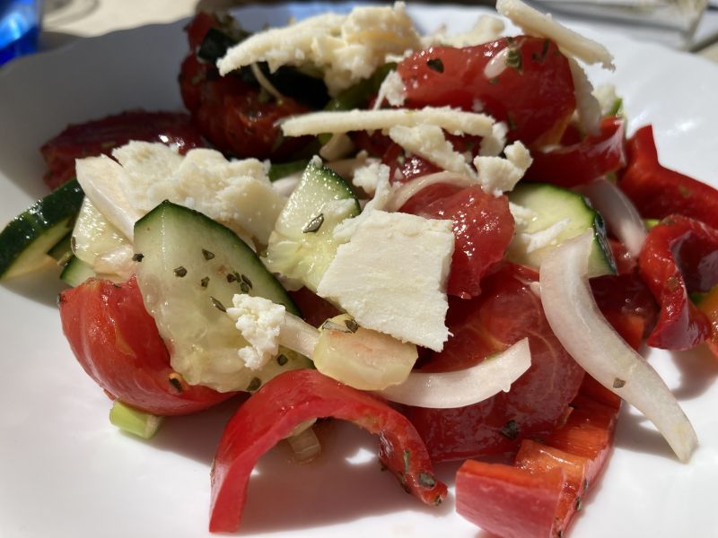 Chopped vegetable salad with pieces of salty white sheep’s cheese sprinkled on top.