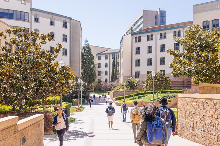 Students move to and fro past residence halls on the Hill.