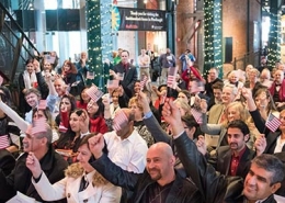 A group of people sit at the Heinz History Center great hall for a citizenship ceremony.