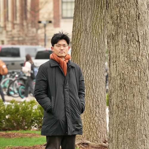 Close-up of Hunsoo Song in front of the pink blossoms of a crabapple tree