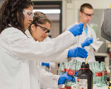 college students pouring liquid in science lab