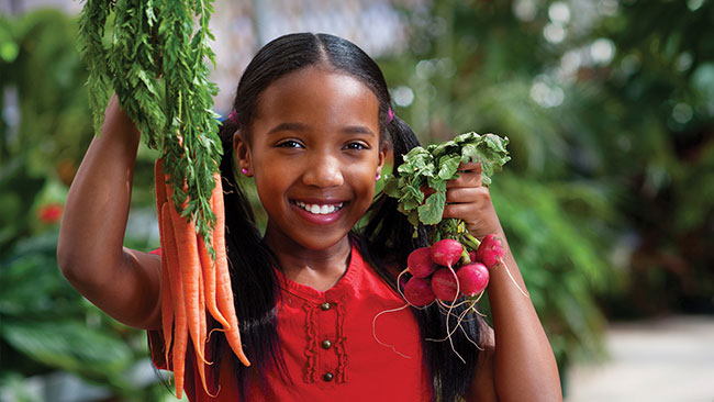 Photo of girl holding up organic produce