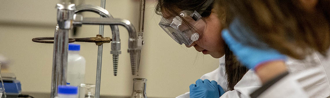 student with goggles working in lab