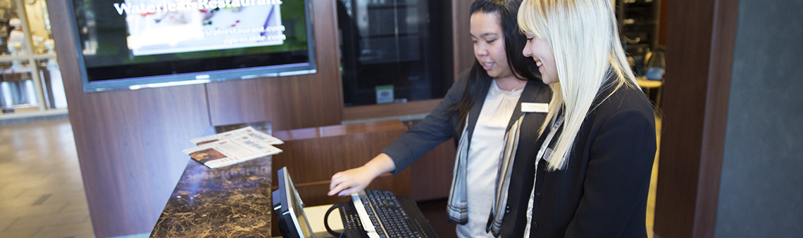 two females at hotel check-in desk