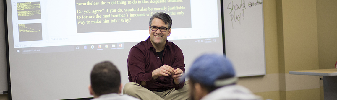 professor smiling at front of classroom