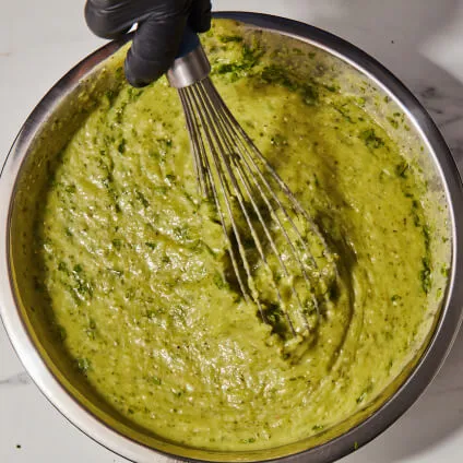 A hand whisking ingredients in a bowl