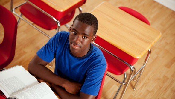 Male college student sitting at desk with text book open