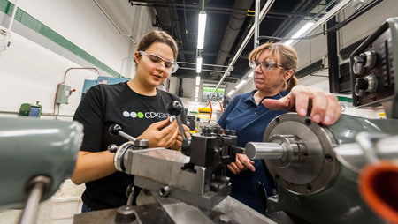 student working with instructor on equipment wearing safety glasses