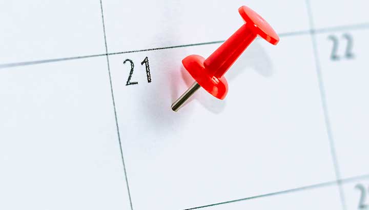 thumb tack pointing at date on calendar