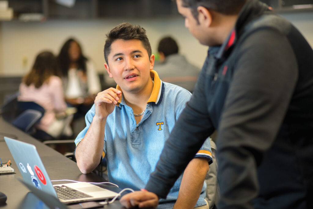 Two students collaborate on a laptop