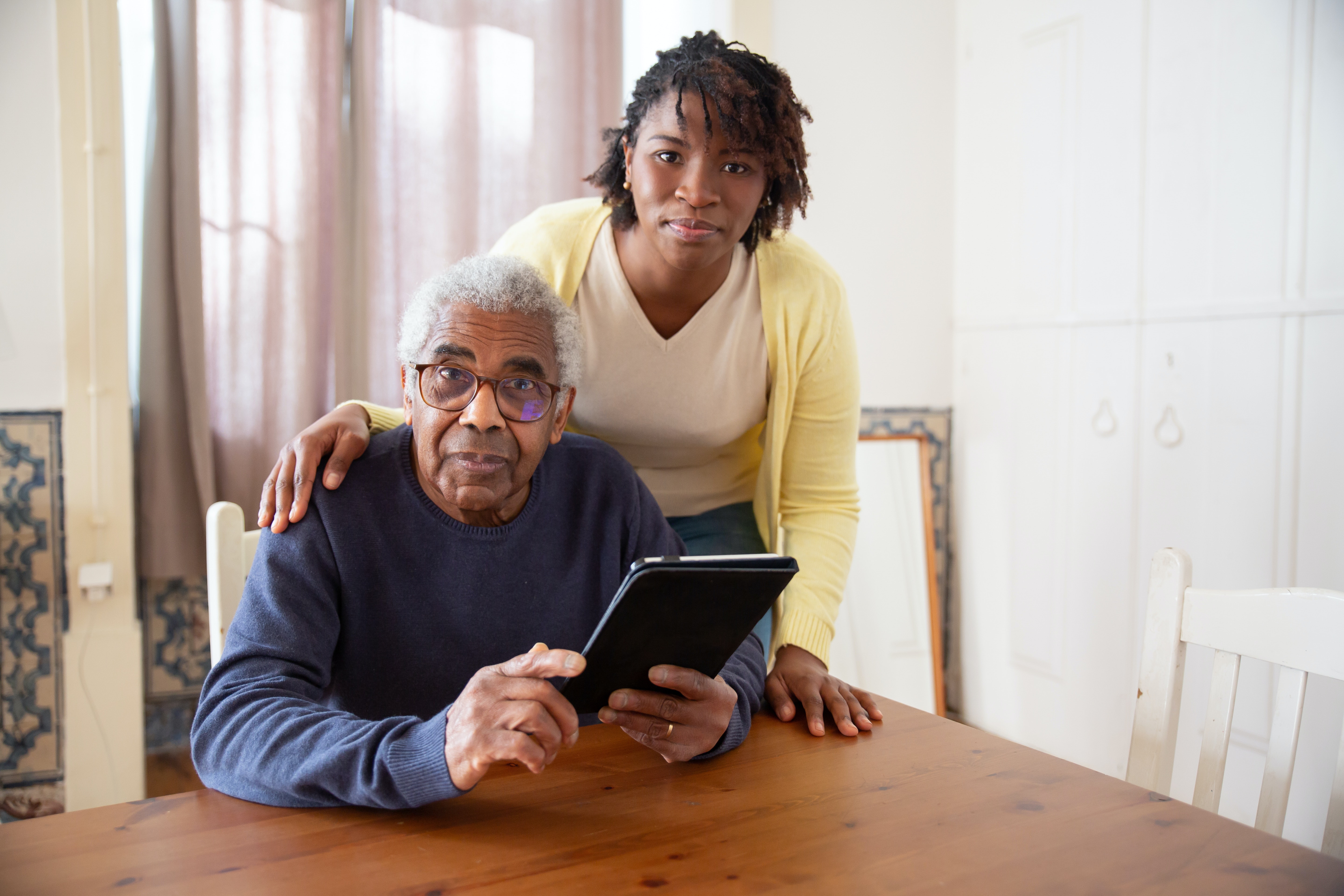 An elderly man poses for a picture with a caregiver