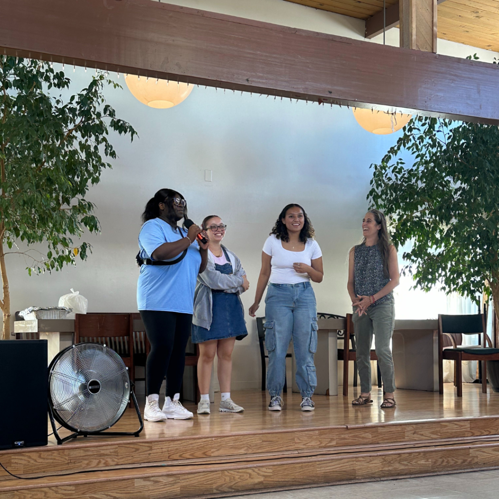 PEARLS scholars stand on a stage as they introduce themselves to the older adults at the IDIC.