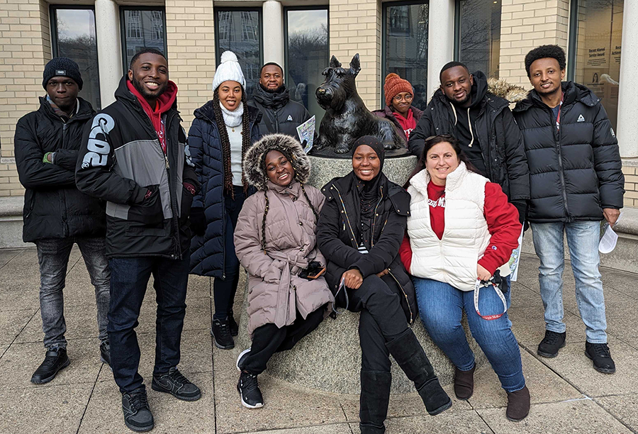 Nine students posing around a scotty dog statue