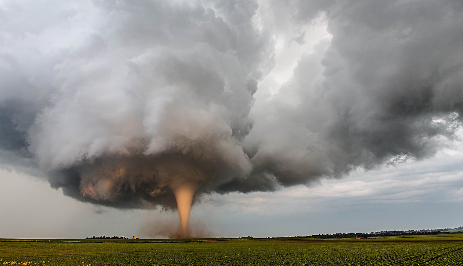 Una enorme nube de tormenta sobre las llanuras con un claro embudo emergiendo de su base.