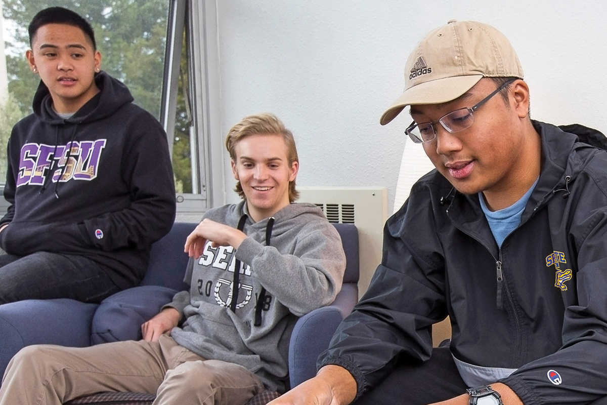 three SF State students looking at a laptop