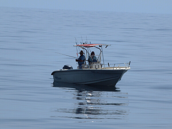 Two people fish from a boat on the ocean