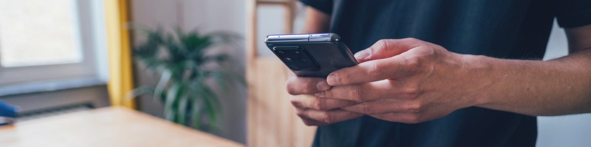 A person's hands holding and typing on a smartphone.