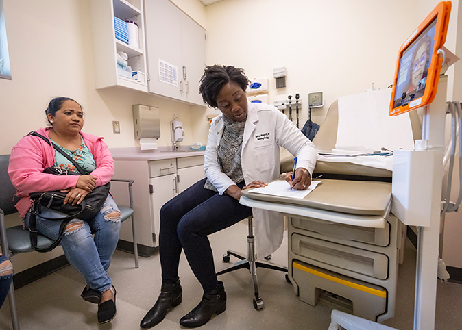 A remote on screen interpreter is speaking to a doctor and patient.