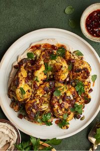 This charred cauliflower with pomegranate tahini sauce, chili crisp honey glaze, fresh herbs, and pepitas makes a great side for any meal. #cauliflower #sidedish #vegetarianrecipe #vegetarianside #healthyrecipe