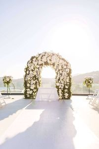 We set the scene with a sea of white orchids, lacing the couple’s ceremonial arch to match Carla’s wedding dress, festooning the terrace of their reception with round mirror surface tables, chandeliers and white bloom arrangements for days. Centerpiece magic brought by tree-branches vested with boules of candles and clear orchid and hydrangea filled vases was implemented with clear glass and gold rimmed dinnerware.