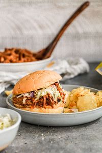 An easy slow cooker pulled pork shoulder recipe with homemade BBQ sauce and slaw. It's the BEST slow cooker pulled pork for a crowd!